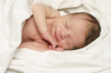 Newborn baby boy smiling in his sleep happy during his nap.