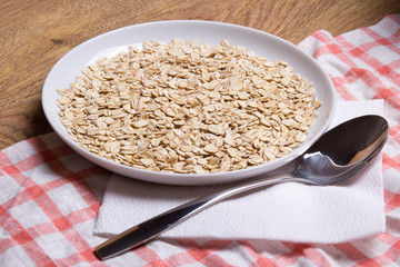 close up of oatmeal in plate with spoon on table