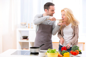 Young attractive man give food to his wife to taste