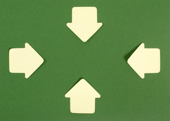 Paper arrows pointing inward. Yellow post it arrows on green.