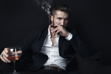 Attraktiver Mann mit Bart raucht Zigarre und trinkt Whiskey