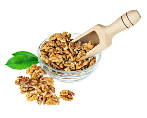 Handful of walnuts in glass bowl, scoop and green leaves.