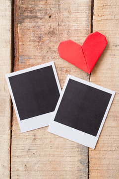 Instant photos with origami hearts. On wooden background