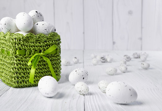 Easter eggs in a green basket on a white table