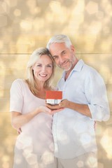Composite image of happy couple holding miniature model house