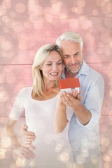 Composite image of happy couple holding miniature model house