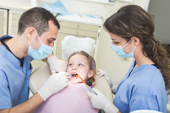 Dentist and Dental Assistant examining Young Girl teeth.