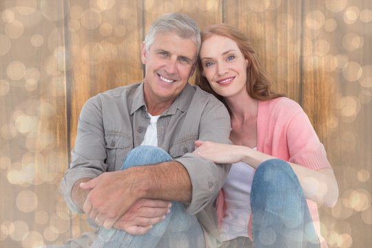 Composite image of casual couple sitting and smiling