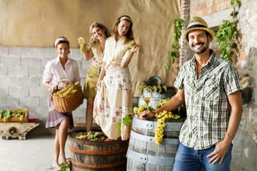 Obraz premium farmer drinks wine while women pounding grapes in an old farm