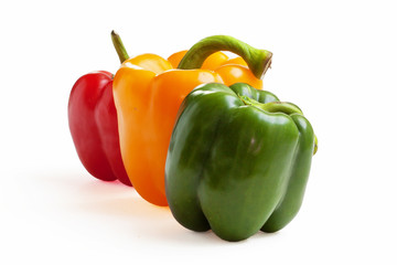 Poivrons de couleurs différentes alignés sur fond blanc