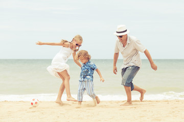 Father and children playing on the beach at the day time.