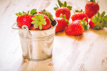 Spring fruits, strawberries in an aluminum bucket on a vintage w