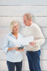 Composite image of mature couple working out their bills