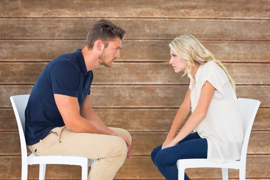 Composite image of young couple sitting in chairs arguing