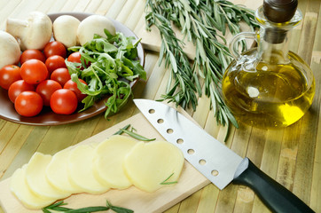 sliced cheese, tomatoes, mushrooms and herbs on a kitchen table