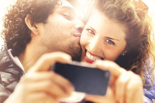 Couple in love making a selfie while him giving her a kiss