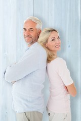 Smiling couple standing leaning backs together