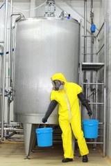 technician in protective uniform with  buckets at process tank