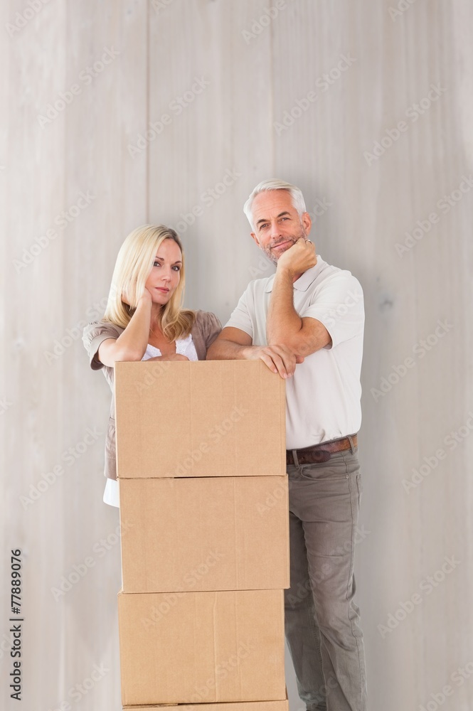 Poster composite image of happy couple leaning on pile of moving boxes