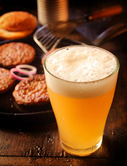 Cold glass of frothy beer with burger patties