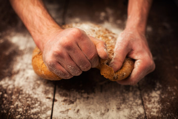 Baker hands with fresh bread on table