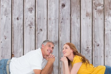 Composite image of casual couple lying on floor