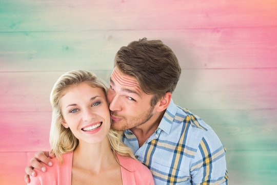 Composite image of handsome man kissing girlfriend on cheek