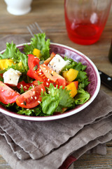 Salad with tomatoes, cheese and greens in a bowl