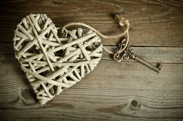 wicker heart handmade with the key lying on a wooden base . top