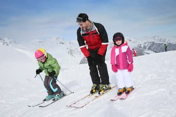 Ski teacher helping young kids to go down ski slope