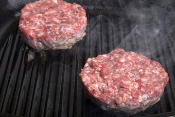 Two beef cutlets on the grill frying pan