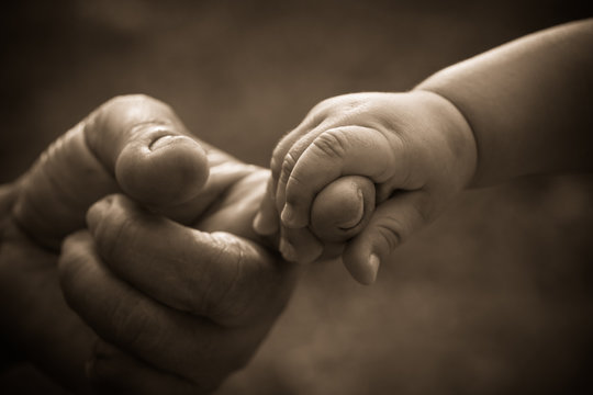 Baby hand holding mother finger with retro effect