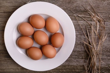 chicken eggs on white plate rustic wooden background with straw