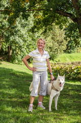Naklejka na ściany i meble Woman with a dog on a walk in the park