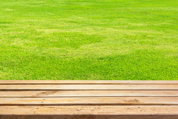 Empty wooden deck table on green grass background