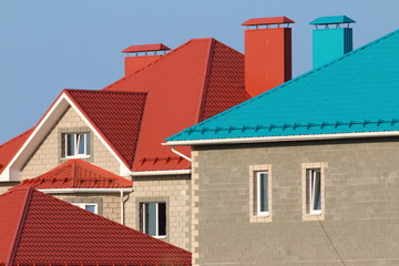 Fototapeta na wymiar Cottages with red and blue roofs against a blue sky