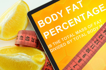 Tablet with words body fat percentage and measuring tape