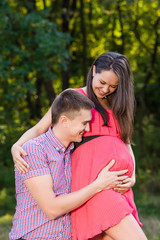 Fototapeta premium Happy and young pregnant couple hugging in nature