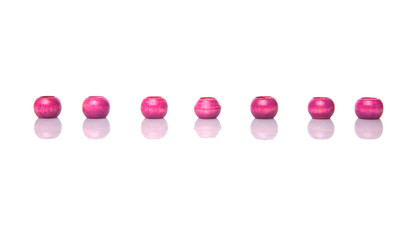 Pink round wooden beads over white background