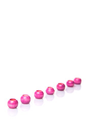Pink round wooden beads over white background