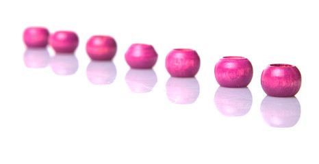 Pink round wooden beads over white background
