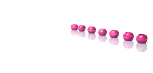Pink round wooden beads over white background
