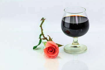 Pink rose and wine in glass on a white background