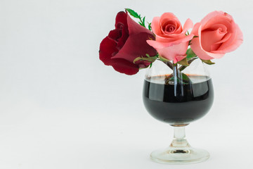 Red rose and pink roses in glass of wine