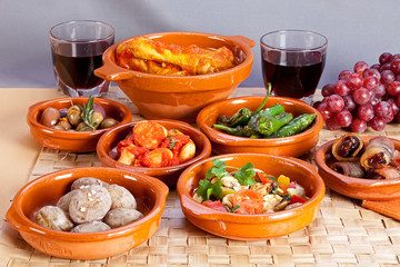 Collection of spanish tapas foods in terracotta bowls.