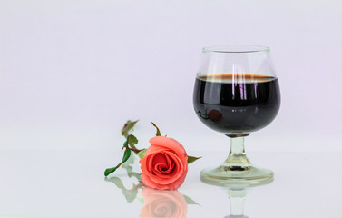 Pink rose and wine in glass on a white background