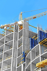 Crane and building construction site against blue sky