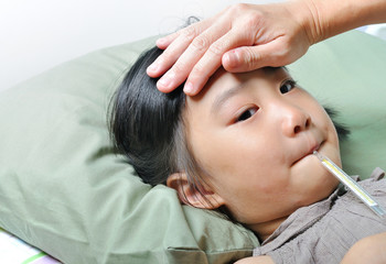 Fototapeta na wymiar Little asain sick girl with temperature in mouth and caring moth