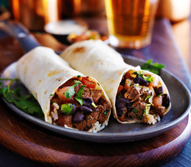 two beef burritos with rice, black beans and salsa