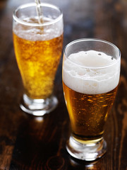 two mugs of amber beer with foam head